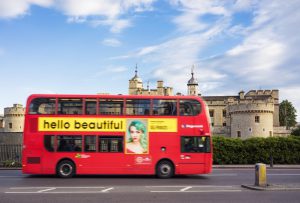 London, UK - May 23, 2014: Motion blur on a red double-decker London bus, featuring advertising by the department store Selfridges, as it passes the Tower of London.